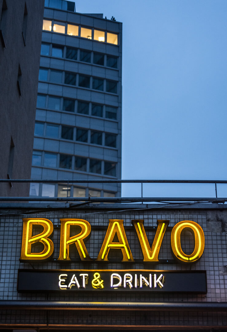 neon-bravo-eat-drink-neon-nad-wejsciem-do-restauracji-neon-na-kaflach-neon-na-scianie-z-kafli-neon-podswietlany-neon-wewnatrz-blachy-nierdzewnej-neon-na-zewnatrz-zolty-neon-warszawa-centralna